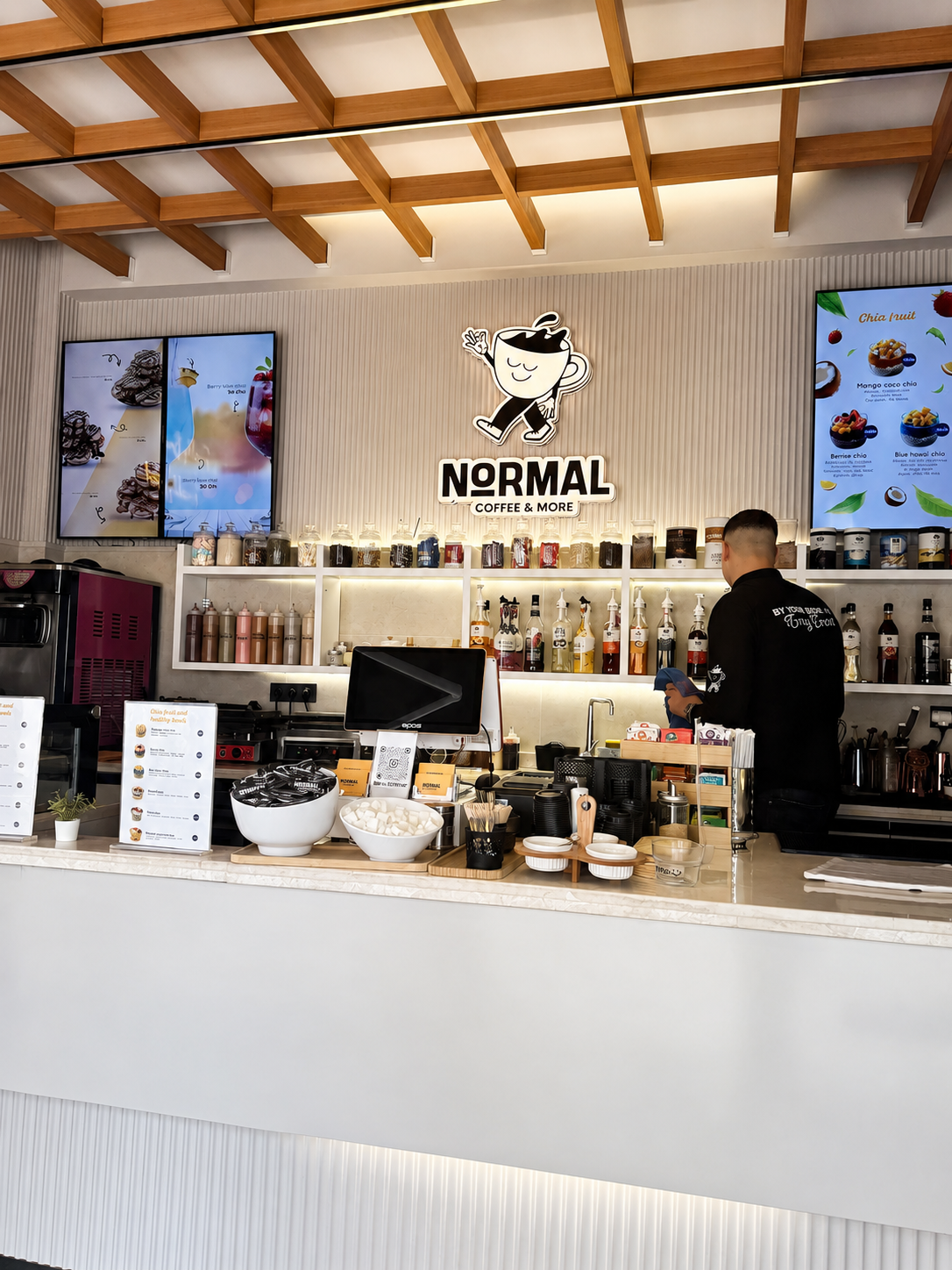 The Normal&More coffee counter with the illuminated logo and wood ceiling